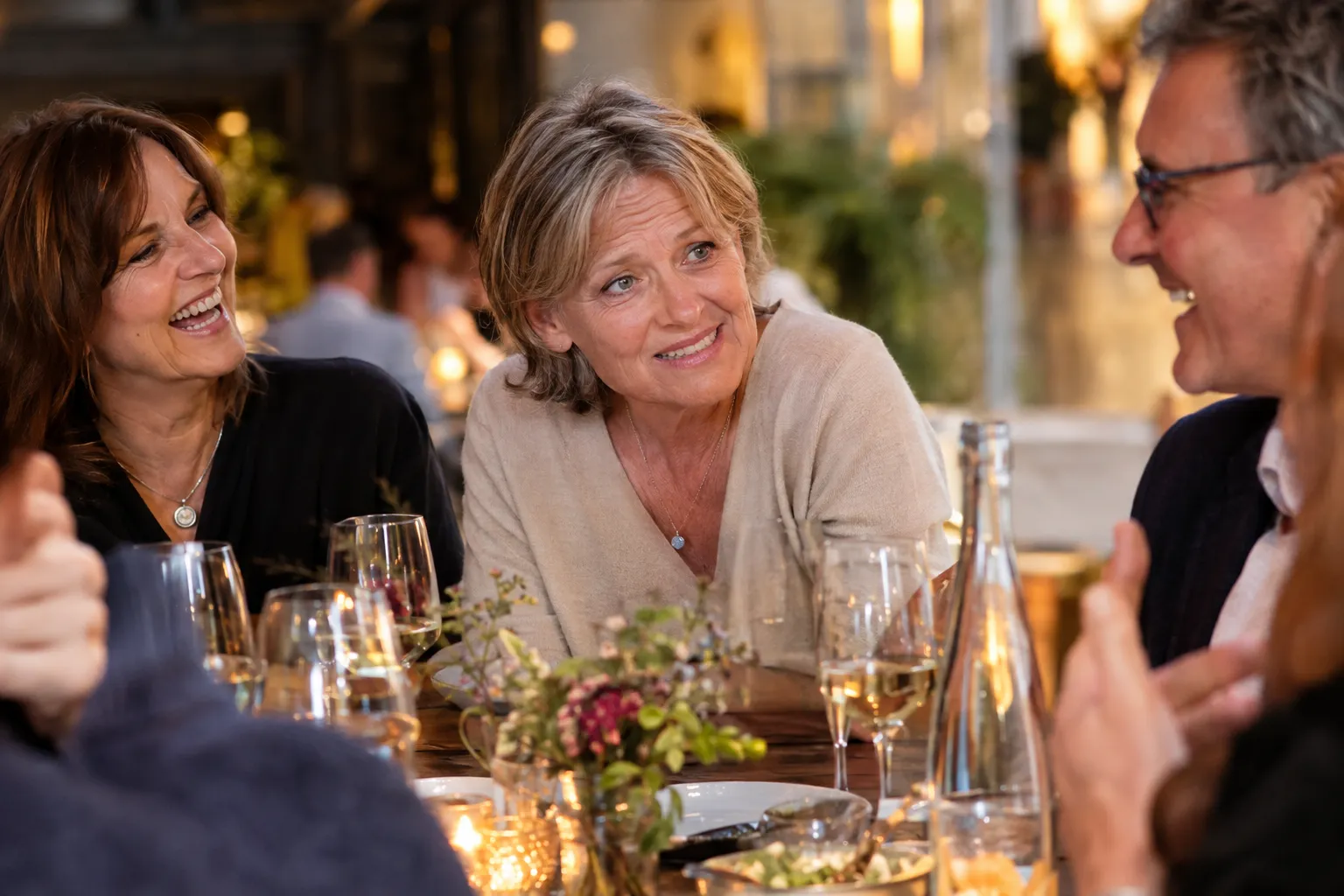 Frau um die 60 im vollen Restaurant, die sich angestrengt zum Gespräch vorbeugt